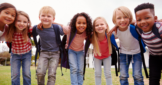 A group of school children standing in a circle smiling.