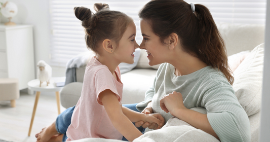 A mother and daughter on the couch smiling and cuddling after naturally treating lice.