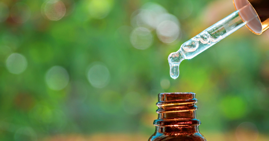 Tea tree oil being dripped with a pipett into a brown bottle.